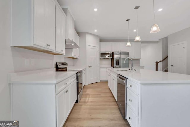 kitchen with white cabinetry, appliances with stainless steel finishes, an island with sink, and hanging light fixtures