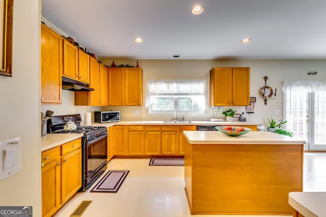 kitchen with light tile patterned flooring, sink, a center island, and black gas range