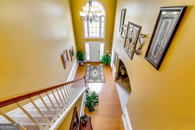 entryway with a towering ceiling, an inviting chandelier, and light wood-type flooring