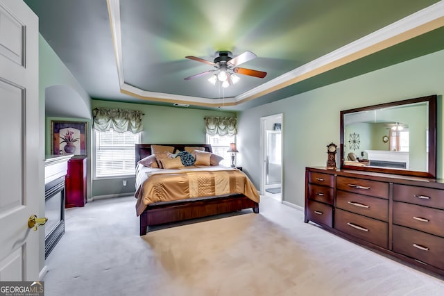 bedroom featuring connected bathroom, light colored carpet, ceiling fan, and a tray ceiling