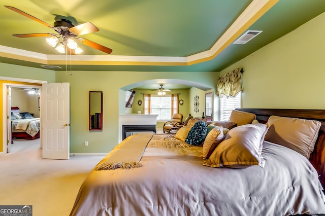 carpeted bedroom featuring crown molding, ceiling fan, and a raised ceiling