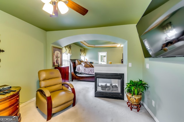 carpeted bedroom with ceiling fan and a multi sided fireplace