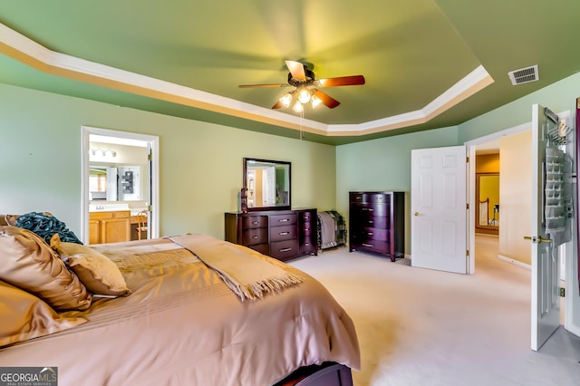 carpeted bedroom featuring ceiling fan, ensuite bathroom, a raised ceiling, and ornamental molding