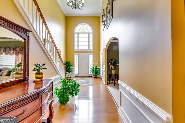 entryway with a notable chandelier, light hardwood / wood-style floors, and a high ceiling