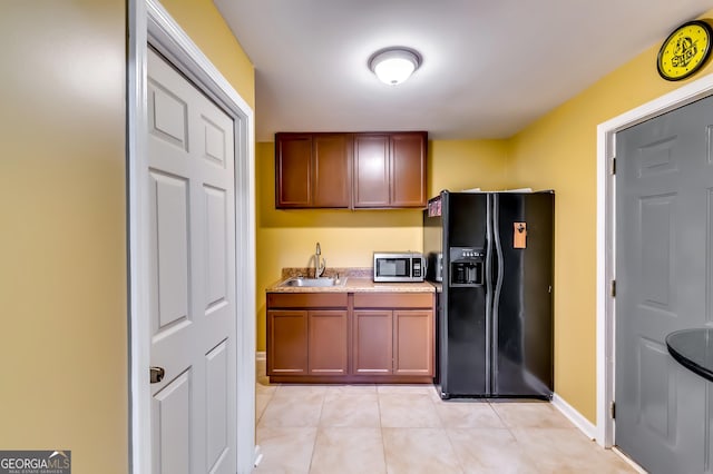 kitchen with black fridge, sink, and light tile patterned floors