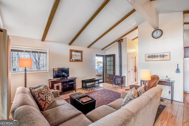 living room with light wood-type flooring, lofted ceiling with beams, and a wood stove