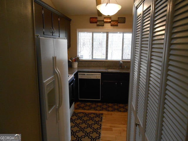 kitchen featuring dishwasher, sink, white refrigerator with ice dispenser, dark brown cabinets, and light hardwood / wood-style flooring