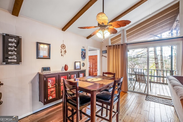 dining space with ceiling fan, vaulted ceiling with beams, and light wood-type flooring