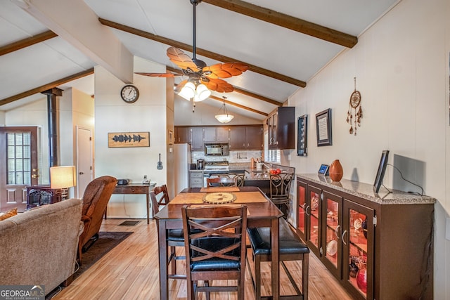 dining room featuring ceiling fan, lofted ceiling with beams, and light wood-type flooring