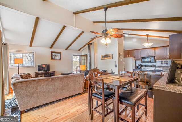 dining room featuring ceiling fan, light hardwood / wood-style flooring, and vaulted ceiling with beams