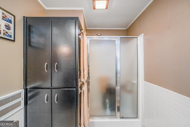 bathroom with tile walls, crown molding, and a shower with door