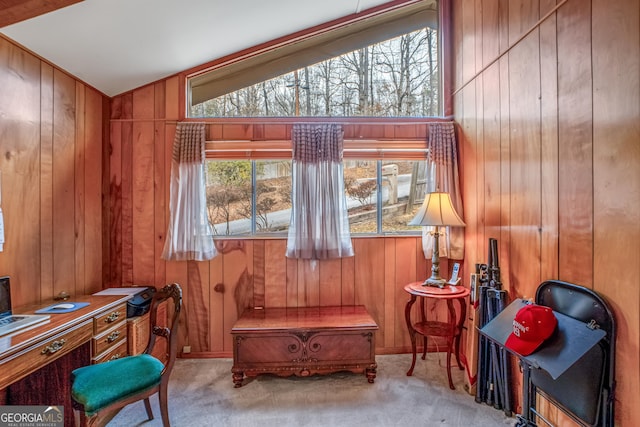 sitting room featuring light colored carpet, wooden walls, and vaulted ceiling