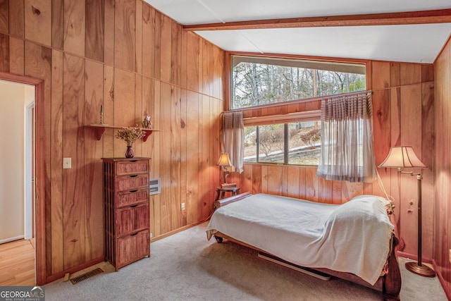 bedroom featuring vaulted ceiling with beams, light colored carpet, and wood walls