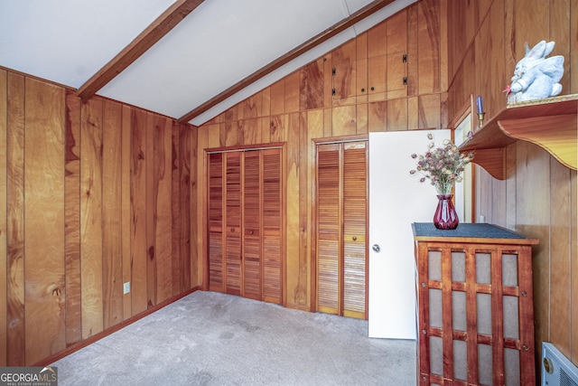 bedroom with two closets, vaulted ceiling with beams, light colored carpet, and wood walls