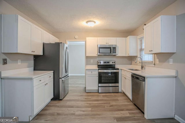 kitchen featuring appliances with stainless steel finishes, sink, a textured ceiling, and white cabinets