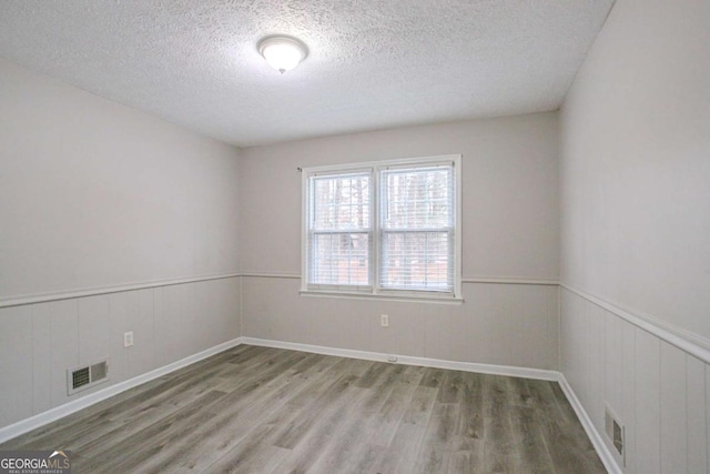 empty room with a textured ceiling and light wood-type flooring