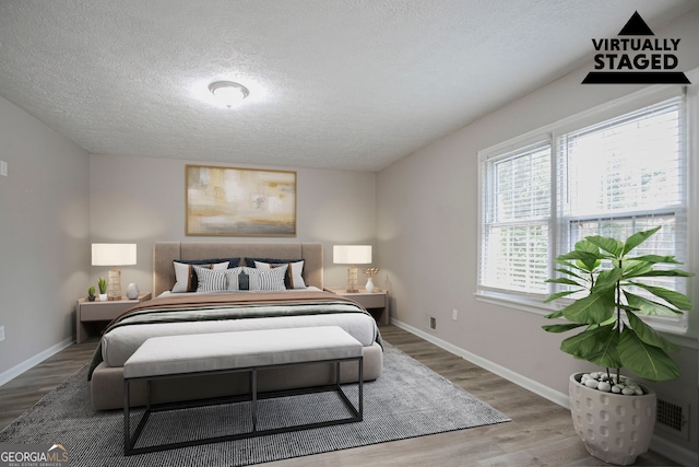 bedroom featuring multiple windows, wood-type flooring, and a textured ceiling