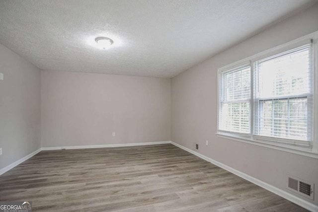 unfurnished room featuring a textured ceiling and light hardwood / wood-style flooring