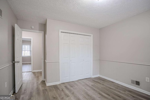 unfurnished bedroom with light hardwood / wood-style flooring, a closet, and a textured ceiling