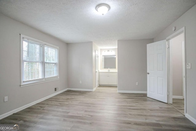 spare room featuring a textured ceiling and light wood-type flooring