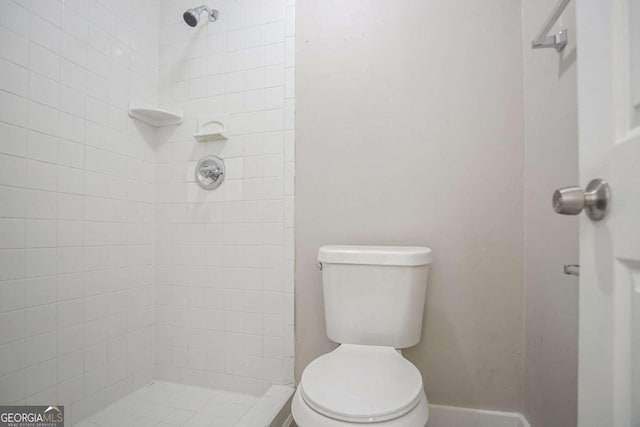 bathroom with a tile shower and toilet