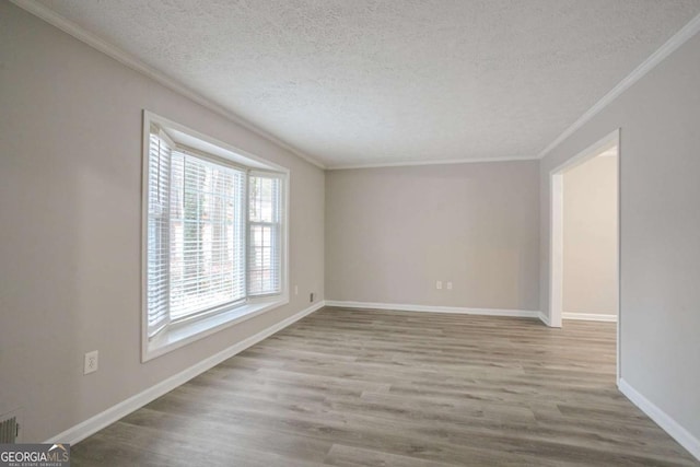 spare room featuring ornamental molding, a textured ceiling, and light hardwood / wood-style floors