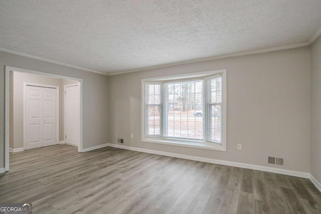 empty room featuring crown molding, hardwood / wood-style floors, and a textured ceiling