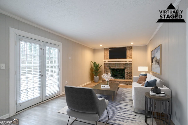 living room with crown molding, wood-type flooring, a textured ceiling, and a fireplace