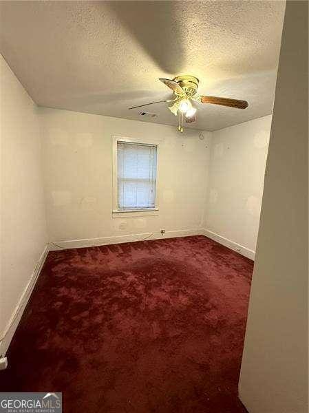 spare room featuring ceiling fan, carpet floors, and a textured ceiling