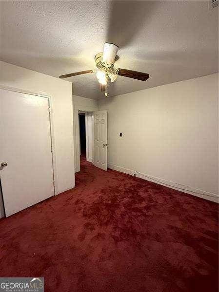 unfurnished bedroom featuring ceiling fan, carpet floors, and a textured ceiling