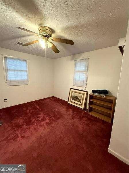 carpeted spare room with ceiling fan and a textured ceiling