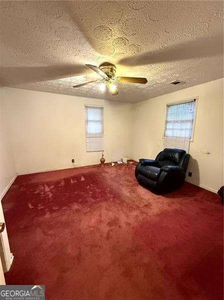 unfurnished room with ceiling fan, carpet flooring, and a textured ceiling