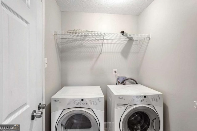 clothes washing area featuring a textured ceiling and washer and clothes dryer