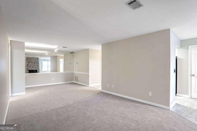 spare room featuring a large fireplace and light colored carpet