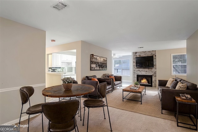 dining space with a large fireplace and light colored carpet