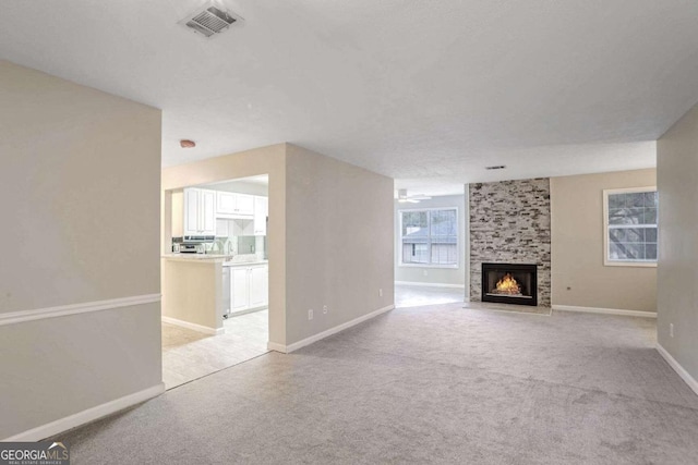 unfurnished living room featuring light carpet and a large fireplace