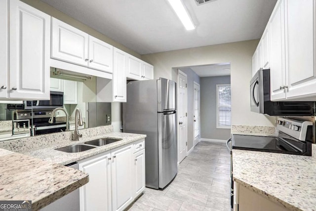 kitchen featuring white cabinetry, appliances with stainless steel finishes, sink, and light stone counters