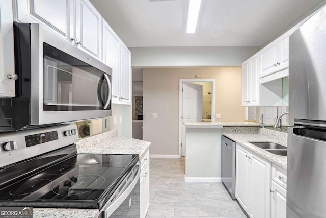 kitchen with white cabinetry, sink, light stone counters, and appliances with stainless steel finishes