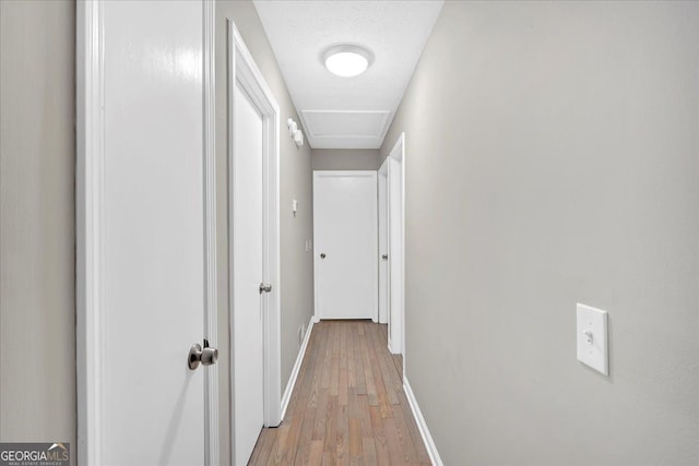 corridor with a textured ceiling and light hardwood / wood-style floors