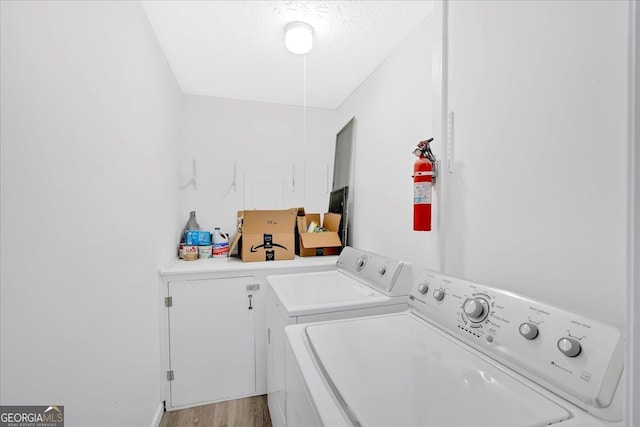 laundry area featuring light wood-type flooring, a textured ceiling, and independent washer and dryer