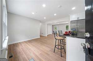 kitchen featuring a breakfast bar area, light wood-type flooring, built in fridge, and white cabinets