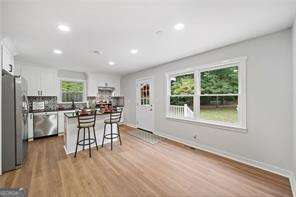 kitchen featuring stainless steel appliances, a kitchen island, light hardwood / wood-style floors, white cabinets, and a kitchen bar