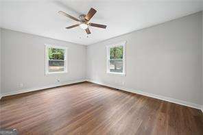 spare room with dark hardwood / wood-style flooring, ceiling fan, and a wealth of natural light