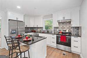 kitchen with a kitchen bar, white cabinetry, stainless steel appliances, and a kitchen island