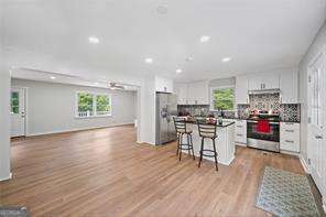 kitchen featuring a kitchen breakfast bar, stainless steel appliances, white cabinets, a center island, and light wood-type flooring