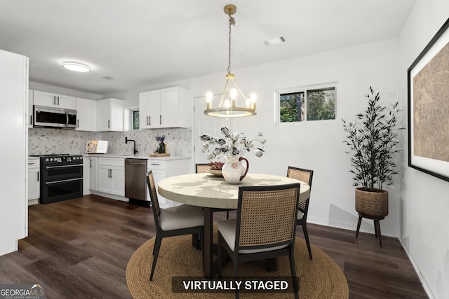 dining area featuring dark hardwood / wood-style flooring, sink, and a chandelier