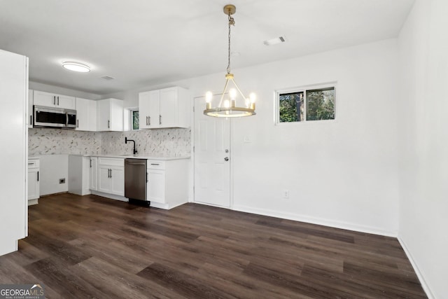 kitchen featuring stainless steel appliances, white cabinetry, pendant lighting, and decorative backsplash