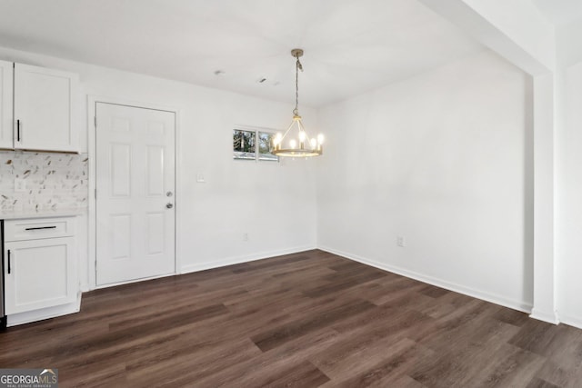 unfurnished dining area with a notable chandelier and dark hardwood / wood-style flooring