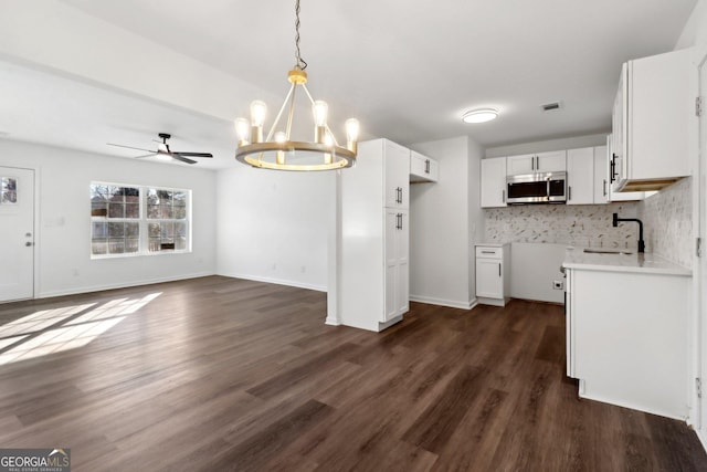 kitchen with ceiling fan with notable chandelier, tasteful backsplash, sink, white cabinets, and dark wood-type flooring