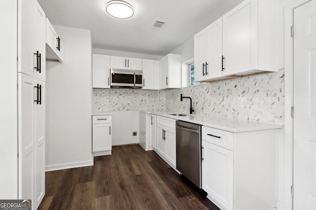 kitchen featuring sink, dark wood-type flooring, appliances with stainless steel finishes, white cabinets, and decorative backsplash